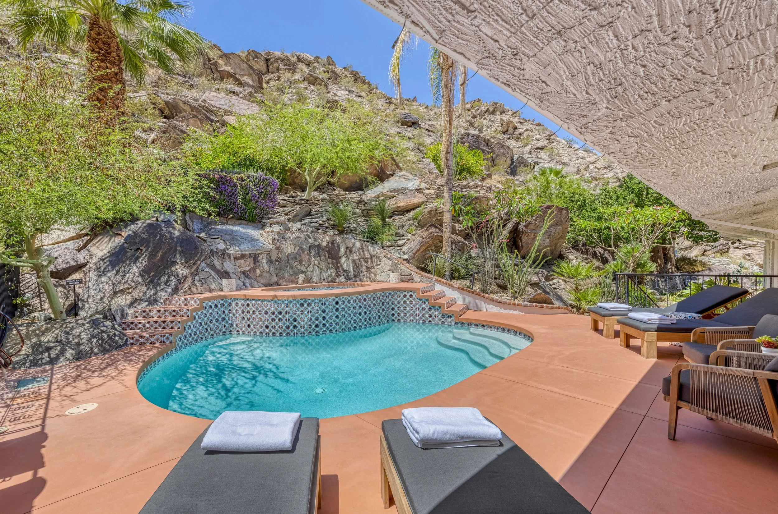 The pool terrace at Ridge House, set against the boulders and desert planting of The Mesa hillside.
